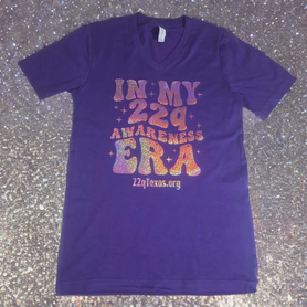 Purple t-shirt with colorful text on a speckled gray surface