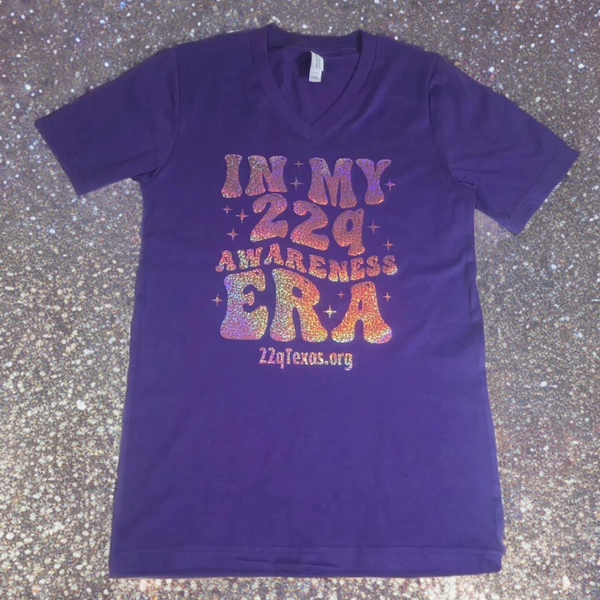 Purple t-shirt with colorful text on a speckled gray surface